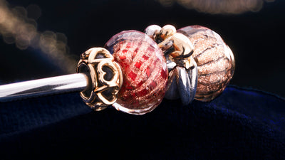 Jonc Trollbeads avec un espaceur coeur en or, des perles en verres à paillettes et une perle maternité en or et argent