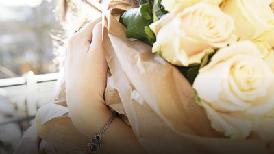 Bouquet de fleurs sur un modèle portant un bracelet Trollbeads