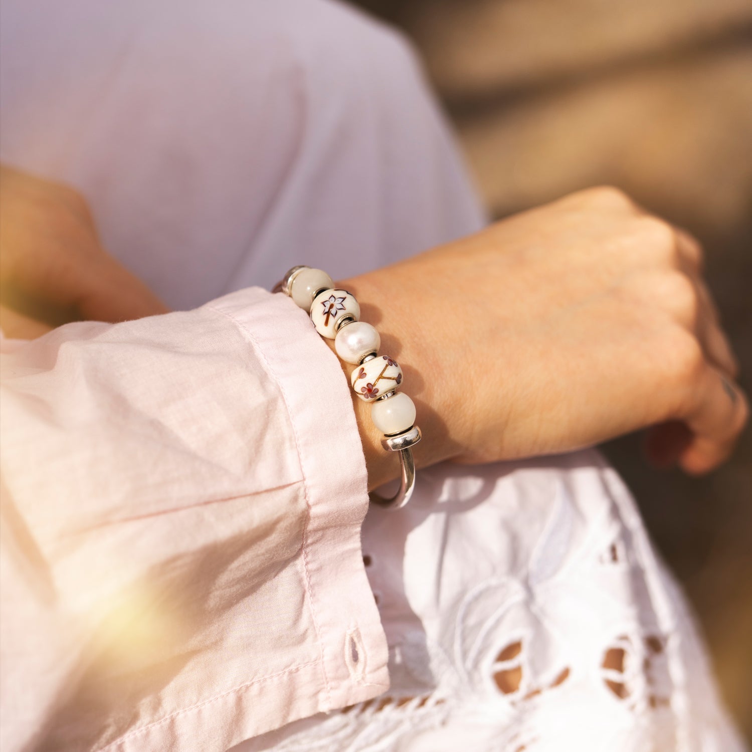 Close-up of a person wearing a bracelet with white beads and a blurred background